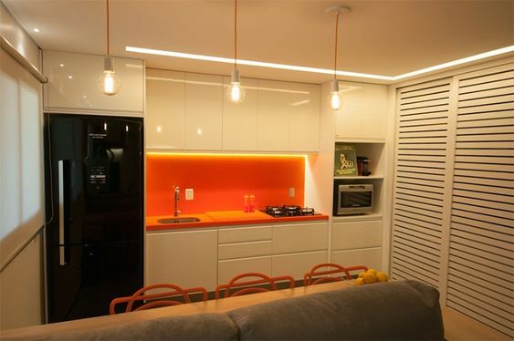 Cozinha com decoração laranja e bege e geladeira preta inverse